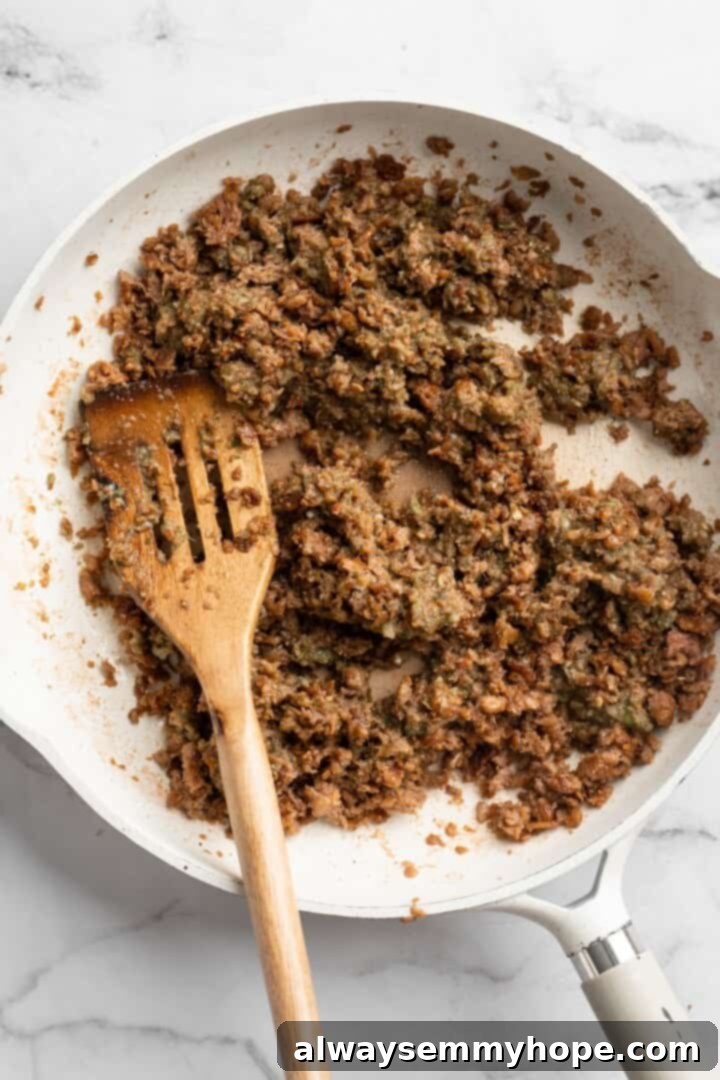 Browning vegan beef in skillet with seasoning mixture for the patty filling