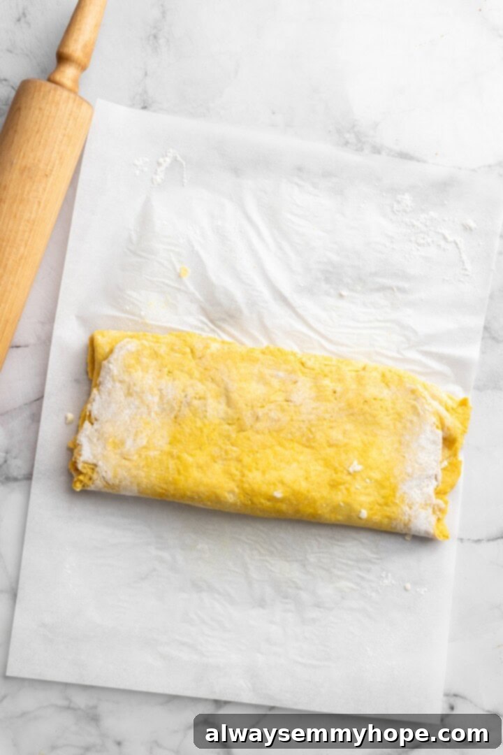 Folded dough on parchment paper, ready for the next rotation in the lamination process