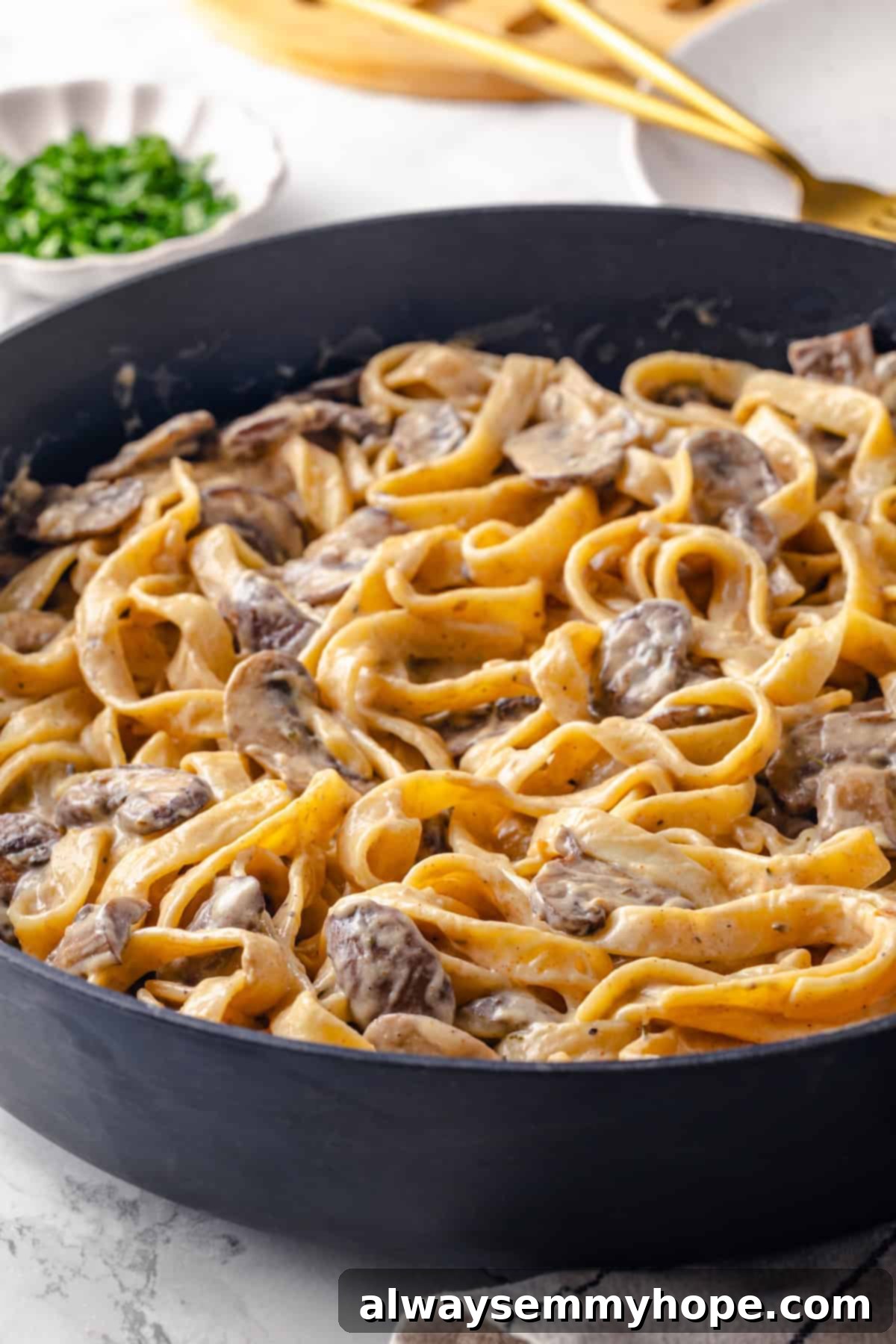 This vegan mushroom stroganoff is packed with umami, rich and creamy, and super satisfying. It’s a cozy recipe you’ll make again and again! Close-up of a skillet filled with a generous portion of vegan mushroom stroganoff, ready to serve.