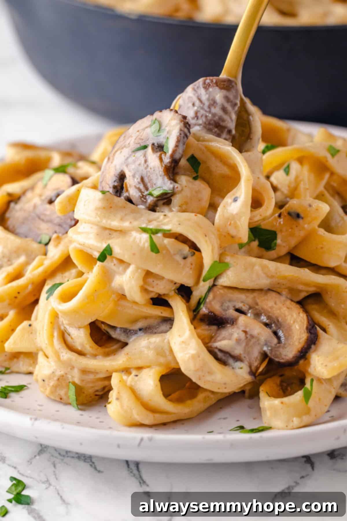 This vegan mushroom stroganoff is packed with umami, rich and creamy, and super satisfying. It’s a cozy recipe you’ll make again and again! Creamy vegan mushroom stroganoff on a white plate with a fork, garnished beautifully.