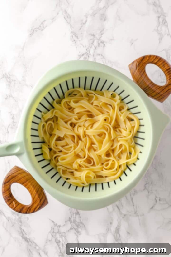 This vegan mushroom stroganoff is packed with umami, rich and creamy, and super satisfying. It’s a cozy recipe you’ll make again and again! Cooked fettuccine pasta in a colander, freshly drained.