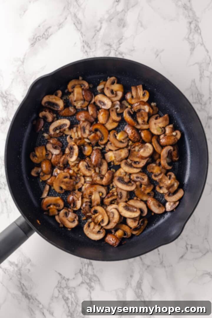 This vegan mushroom stroganoff is packed with umami, rich and creamy, and super satisfying. It’s a cozy recipe you’ll make again and again! Sautéed onions, garlic, and sliced mushrooms browning in a large skillet.