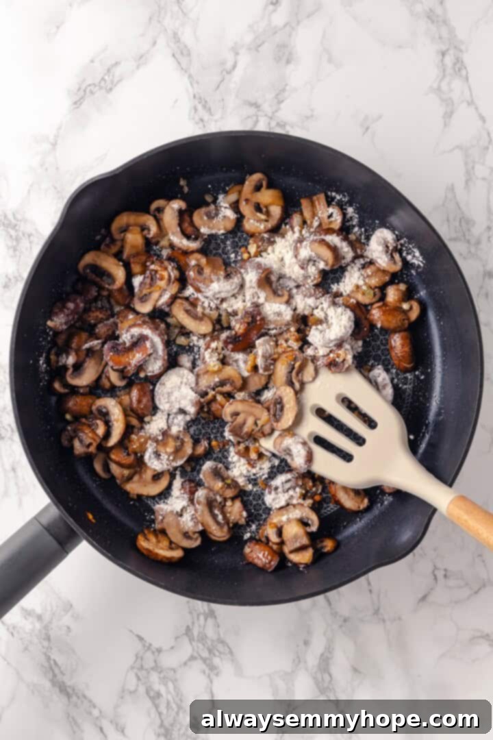 This vegan mushroom stroganoff is packed with umami, rich and creamy, and super satisfying. It’s a cozy recipe you’ll make again and again! All-purpose flour sprinkled over sautéed mushrooms in a skillet, ready to form a roux.