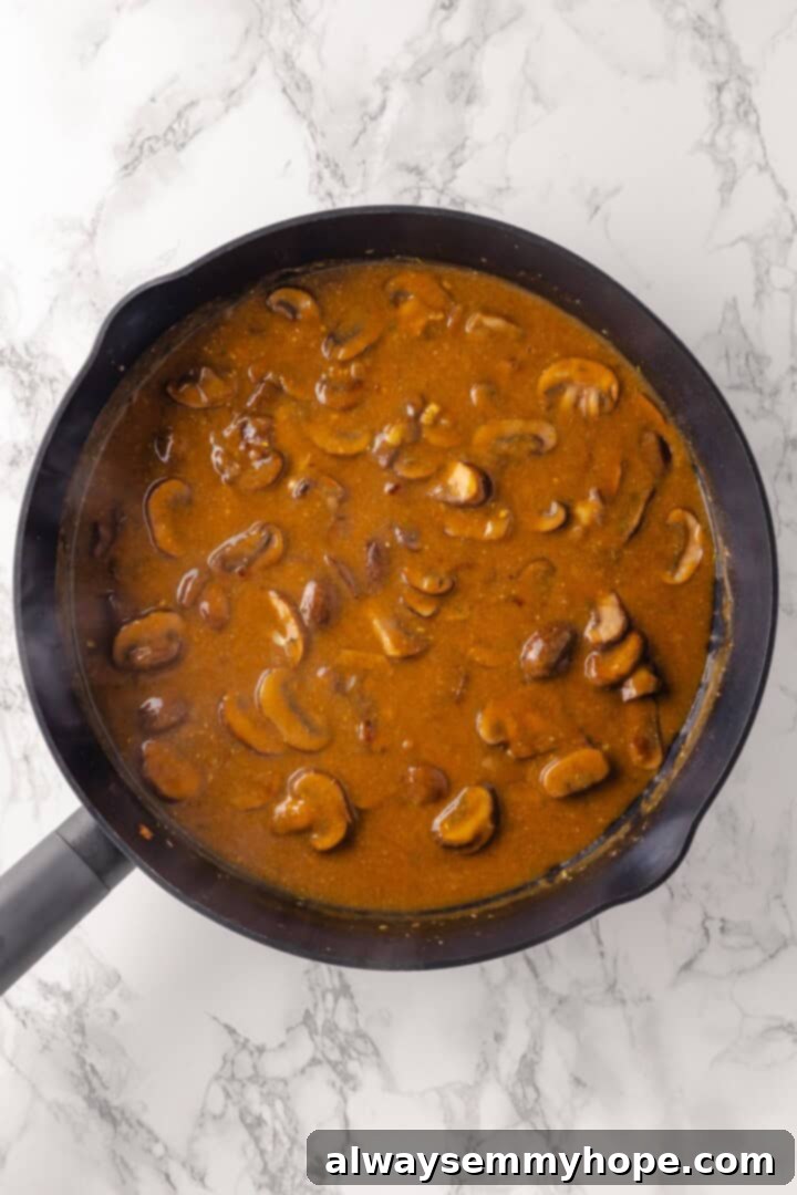 This vegan mushroom stroganoff is packed with umami, rich and creamy, and super satisfying. It’s a cozy recipe you’ll make again and again! Rich mushroom sauce simmering in a skillet after wine and broth have been added.