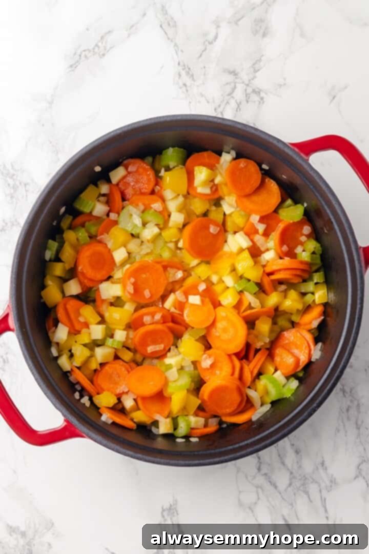 Overhead view of diced vegetables softening in olive oil in a large pot.