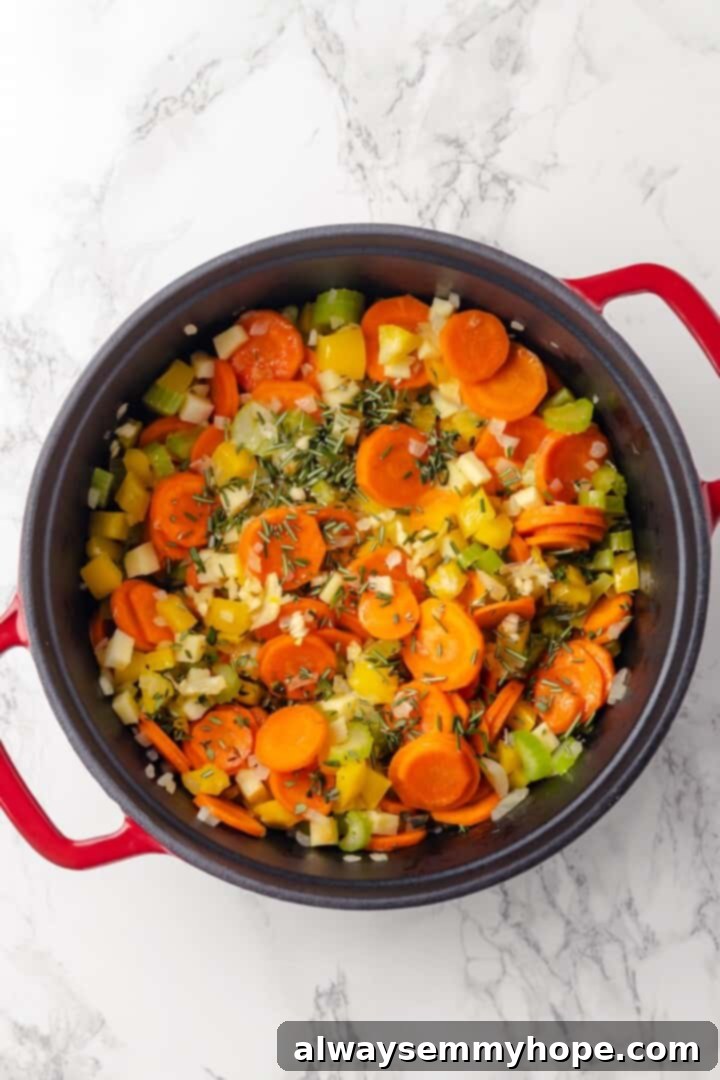 Overhead view of aromatic garlic and fresh herbs added to sautéed vegetables in a pot.