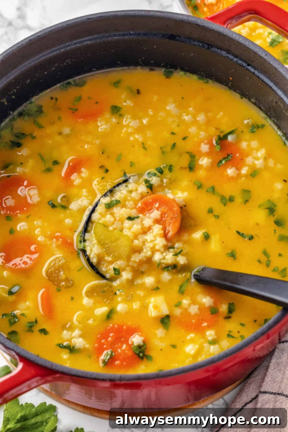 Large pot of vegan Italian penicillin soup with a ladle, ready to be served.