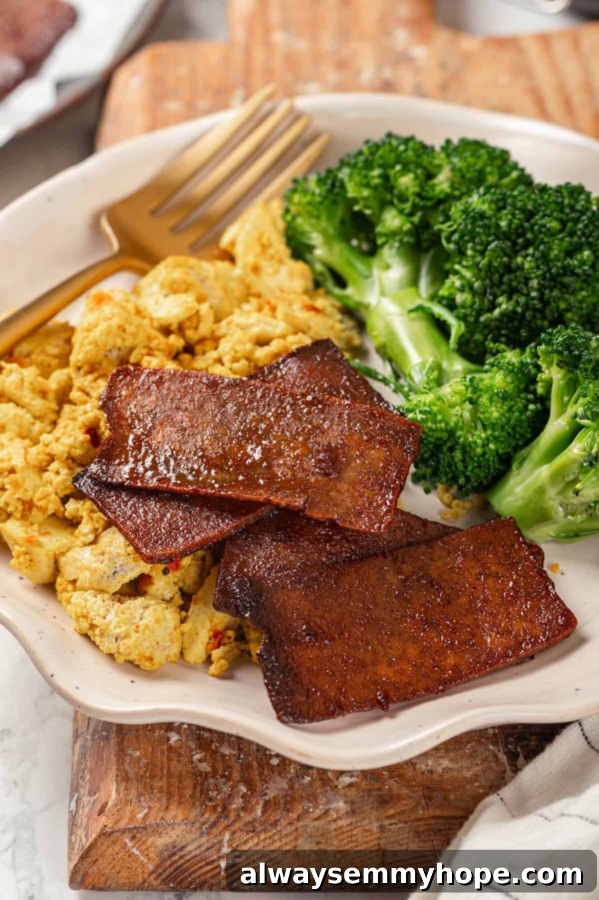 Delicious Vegan Tofu Bacon with Scramble and Broccoli A plate featuring a vibrant vegan scramble, fresh green broccoli, and crispy homemade tofu bacon, perfectly arranged for a wholesome breakfast.