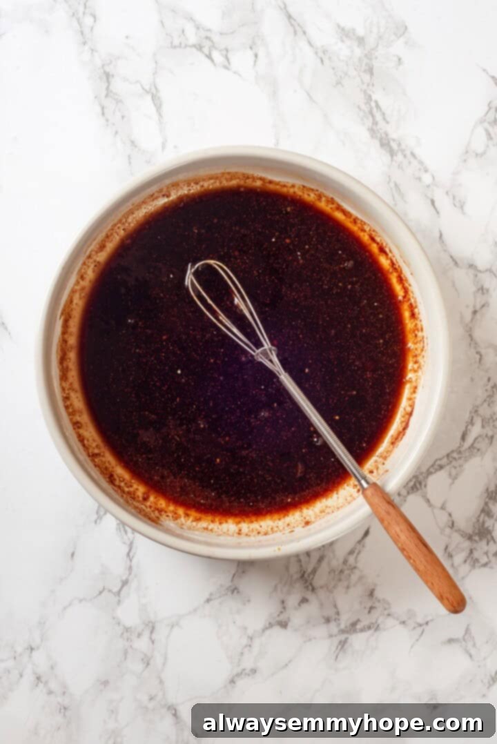 Preparing the Smoky Tofu Marinade An overhead view of a shallow bowl containing a rich, dark marinade, ready for tofu slices to be added.