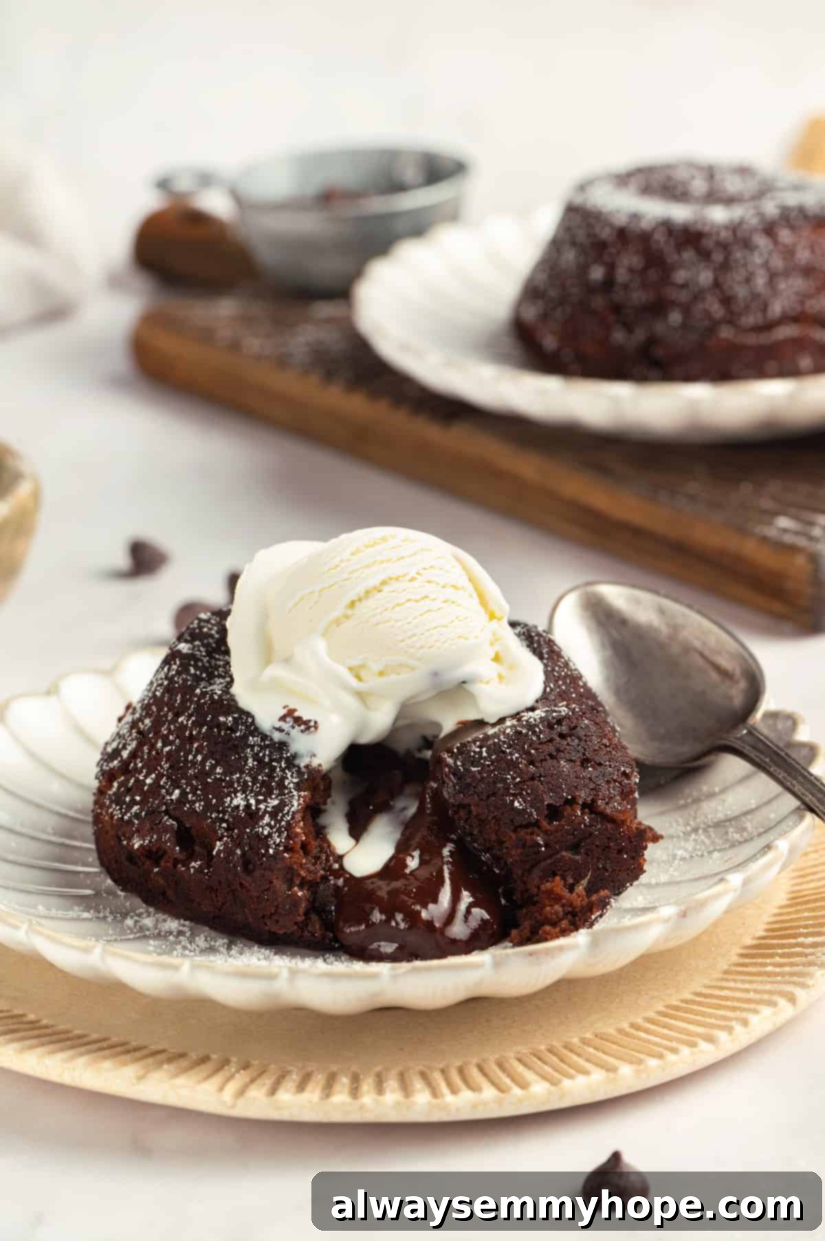 A stunning vegan chocolate lava cake, ready to be enjoyed. A perfectly inverted vegan chocolate lava cake on a white plate, revealing its soft, dark chocolate exterior, with a scoop of vegan ice cream and a garnish of fresh raspberries.