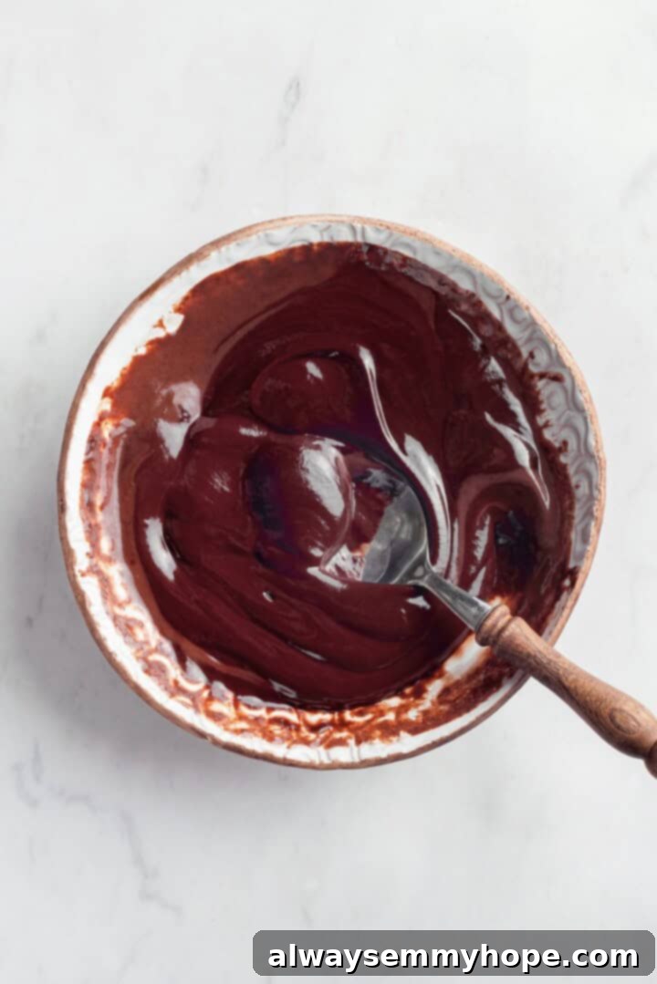 Whipping up the delicious vegan ganache. Smooth, rich vegan chocolate ganache in a white bowl with a spoon, ready to be chilled for the lava cake center.