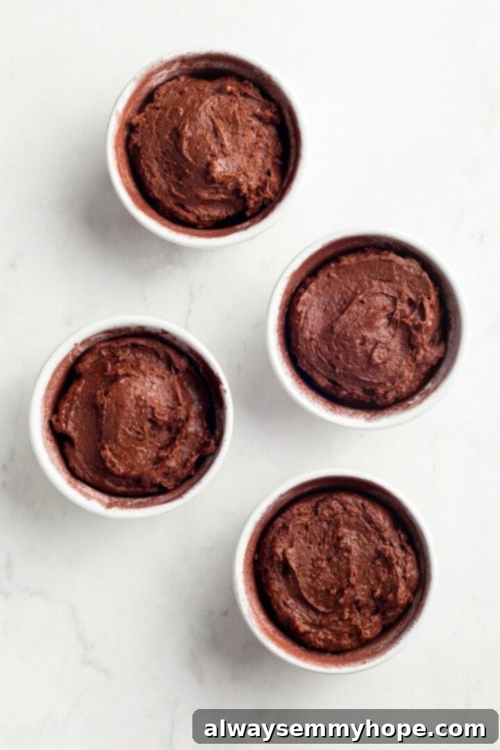 Unbaked chocolate lava cakes in ramekins, ready for baking. Overhead view of four unbaked vegan chocolate lava cakes in ramekins, neatly arranged on a baking sheet, ready for the oven.