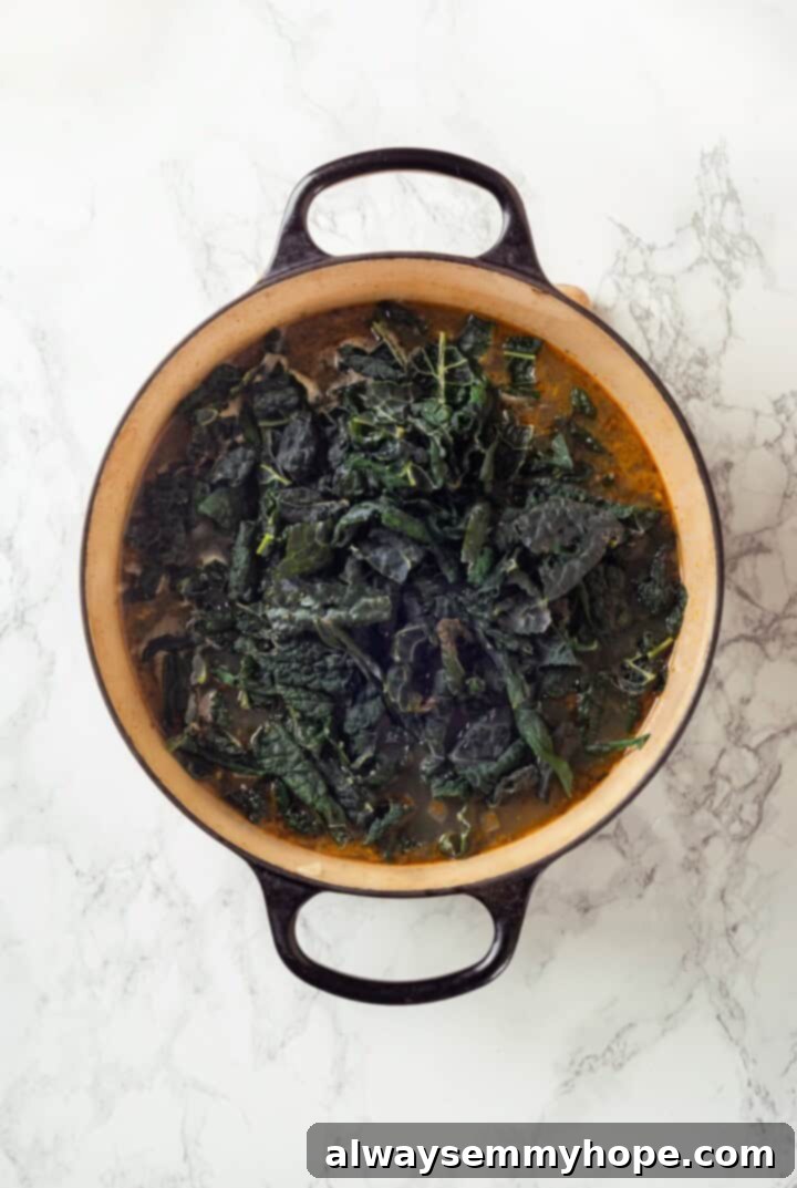 Overhead view of kale added to pot of soup