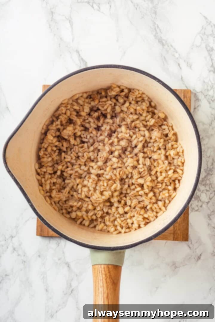 This farro salad is hearty and satisfying, with bright and bold Greek flavours to make it delicious. It might just be the perfect lunch! Overhead view of farro simmering in a pan, absorbing flavorful broth