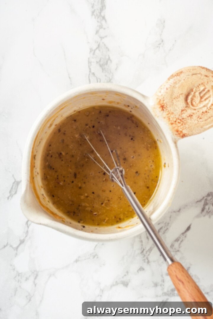 This farro salad is hearty and satisfying, with bright and bold Greek flavours to make it delicious. It might just be the perfect lunch! Overhead view of a small bowl of vibrant lemon vinaigrette with a whisk