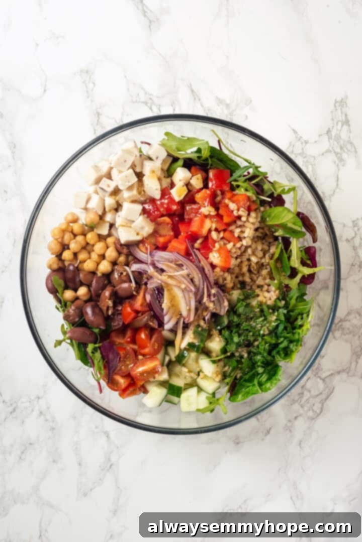 This farro salad is hearty and satisfying, with bright and bold Greek flavours to make it delicious. It might just be the perfect lunch! Overhead view of all Greek farro salad ingredients neatly combined in a large mixing bowl before dressing