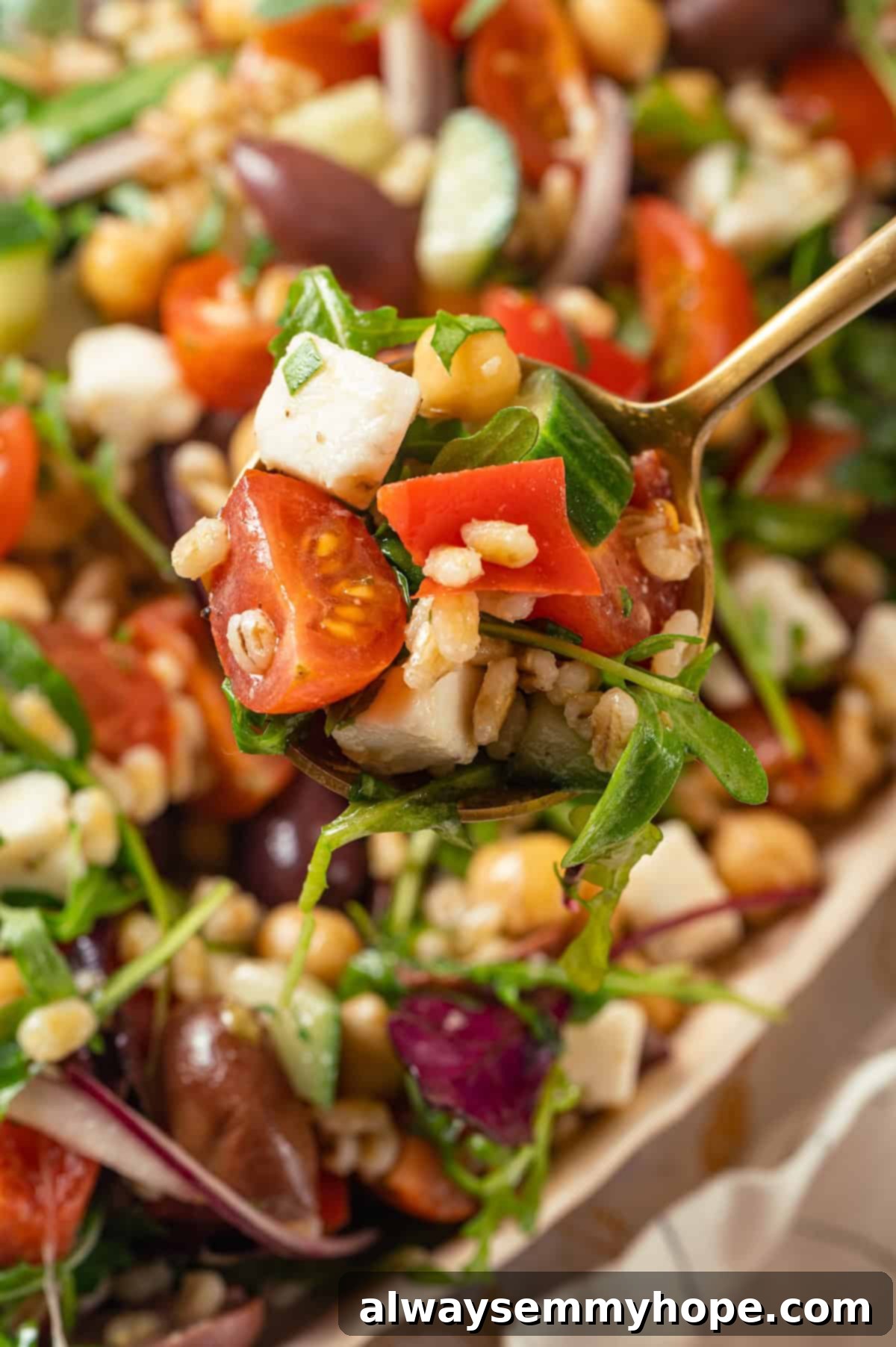 This farro salad is hearty and satisfying, with bright and bold Greek flavours to make it delicious. It might just be the perfect lunch! Close-up of a spoonful of Greek farro salad, showcasing its vibrant ingredients and chewy texture