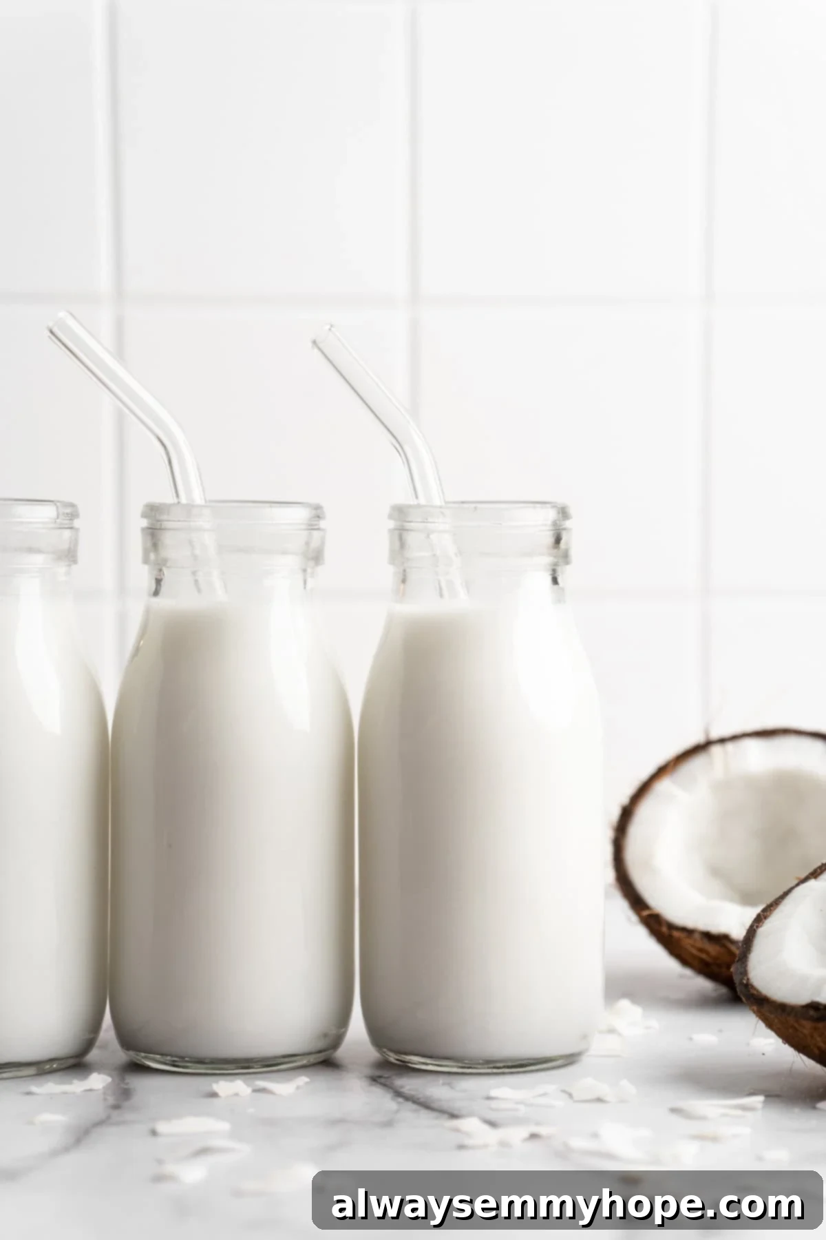 Three glass bottles of homemade coconut milk lined up on a kitchen counter, ready for use or storage.