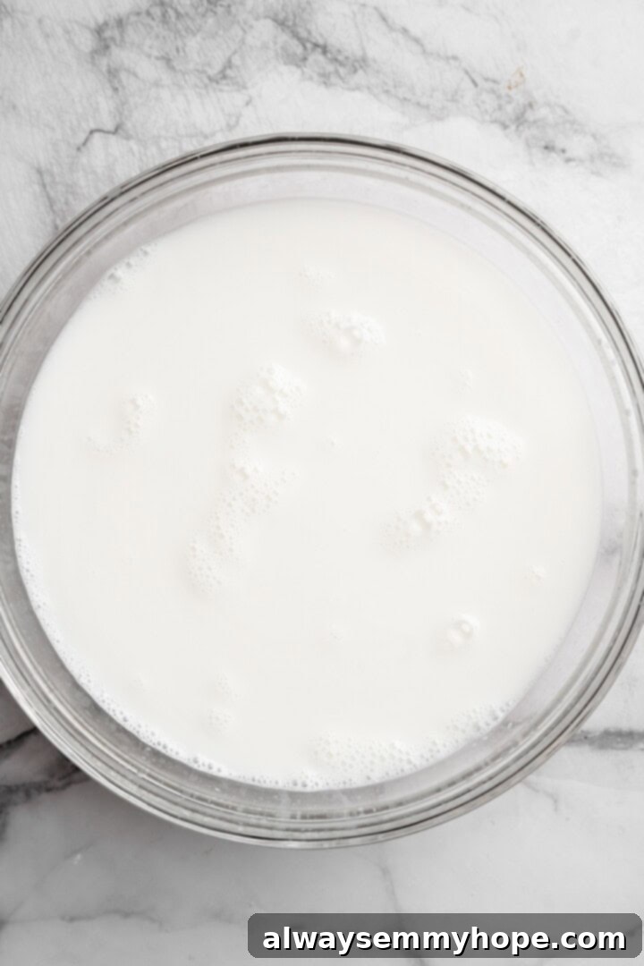Overhead view of freshly strained homemade coconut milk in a clear glass jar, ready for storage.