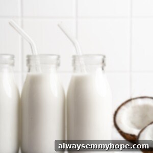 Three glass bottles of homemade coconut milk lined up on a kitchen counter