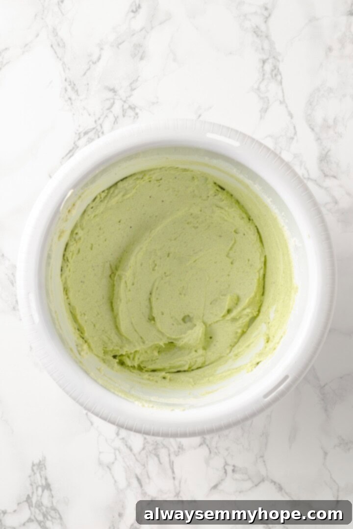 Overhead view of pistachio frosting in mixing bowl before adding powdered sugar