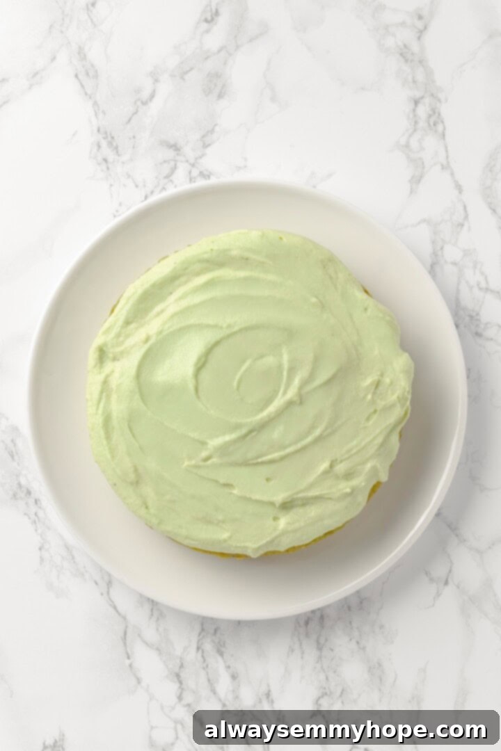 Overhead view of pistachio cake on cake plate before adding pistachio garnish