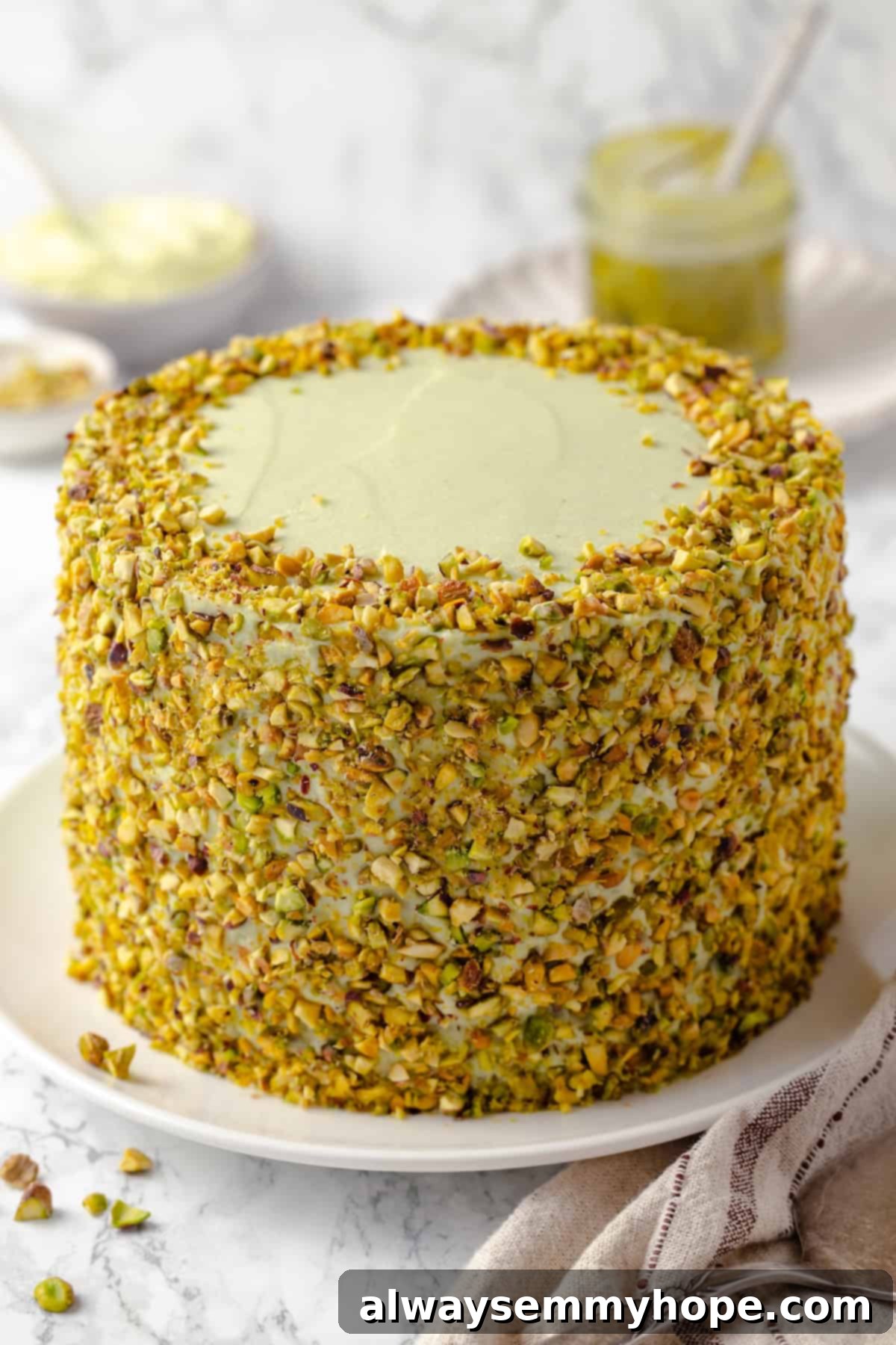 Whole pistachio cake on platter before slicing