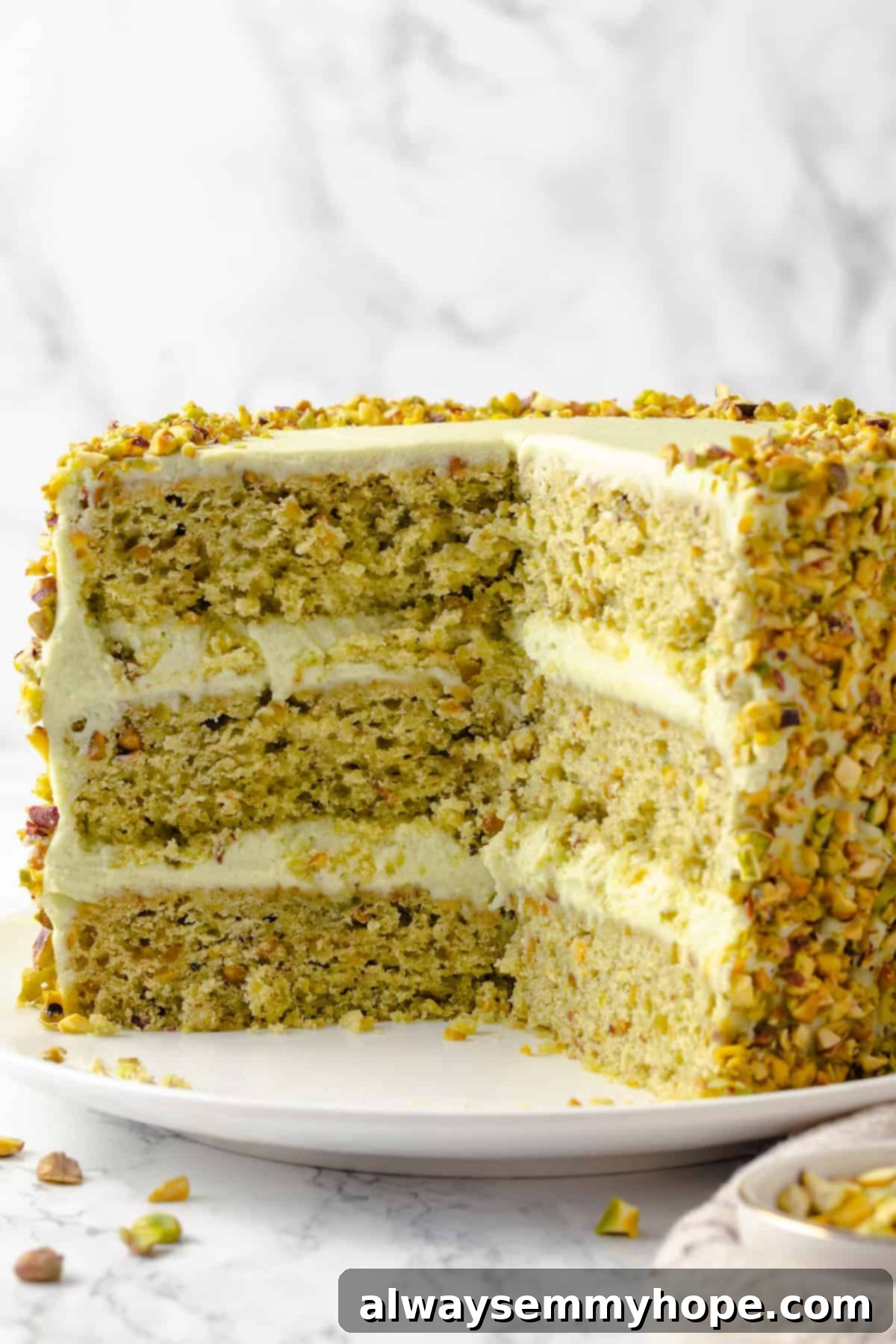 Vegan pistachio cake on plate with slices removed to show layers