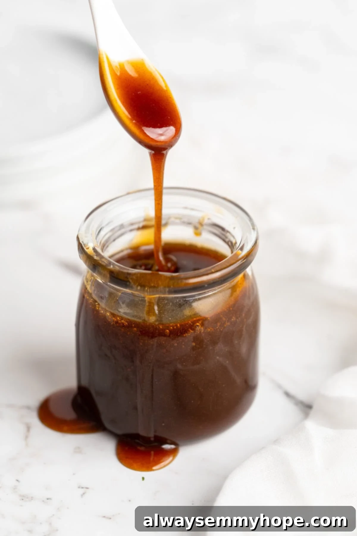 Spoon drizzling rich, amber date syrup into a glass jar