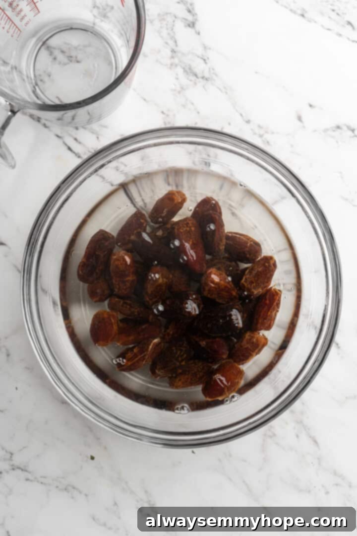 Overhead view of dates soaking in hot water in a saucepan, beginning to soften and infuse the liquid