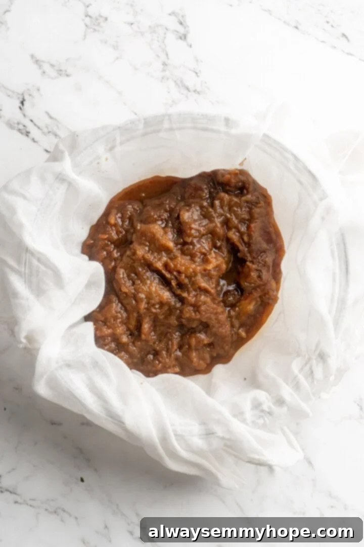 Overhead view of date pulp held in cheesecloth over a bowl, illustrating the straining process
