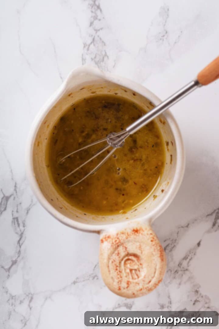 Small bowl with dressing for orzo salad with whisk