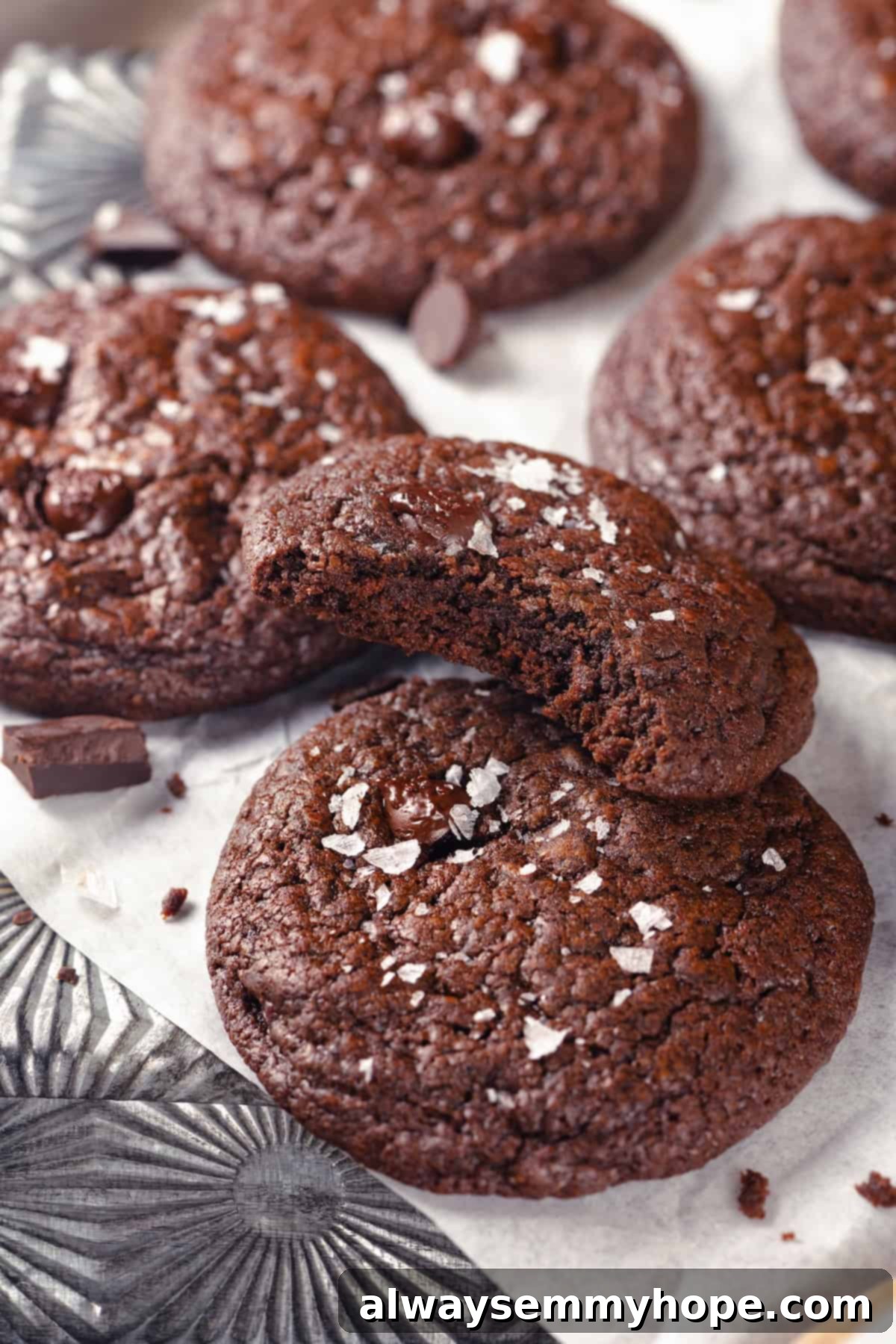 Brownie cookies on parchment, with one cookie bitten into to show fudgy texture