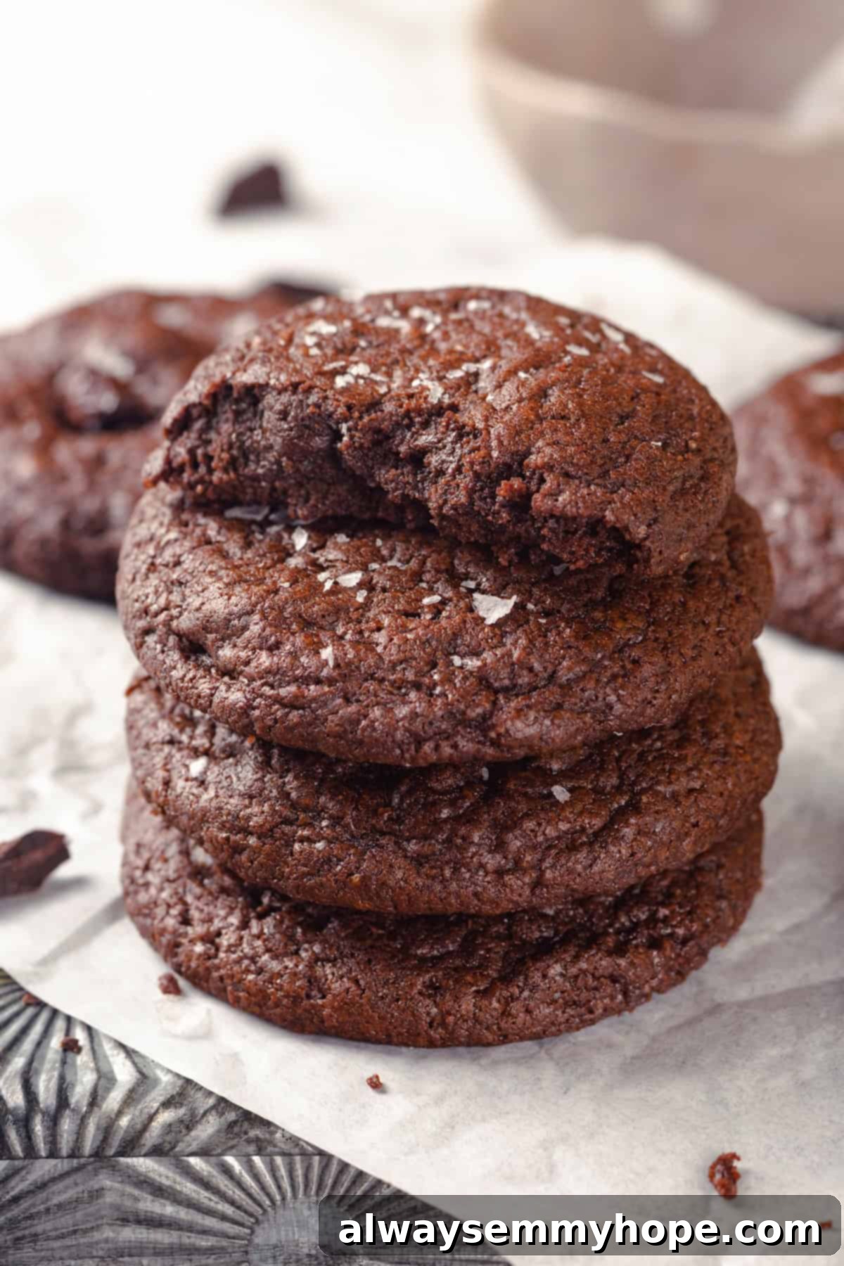 Stack of thick, chewy brownie cookies with top cookie broken in half to show texture