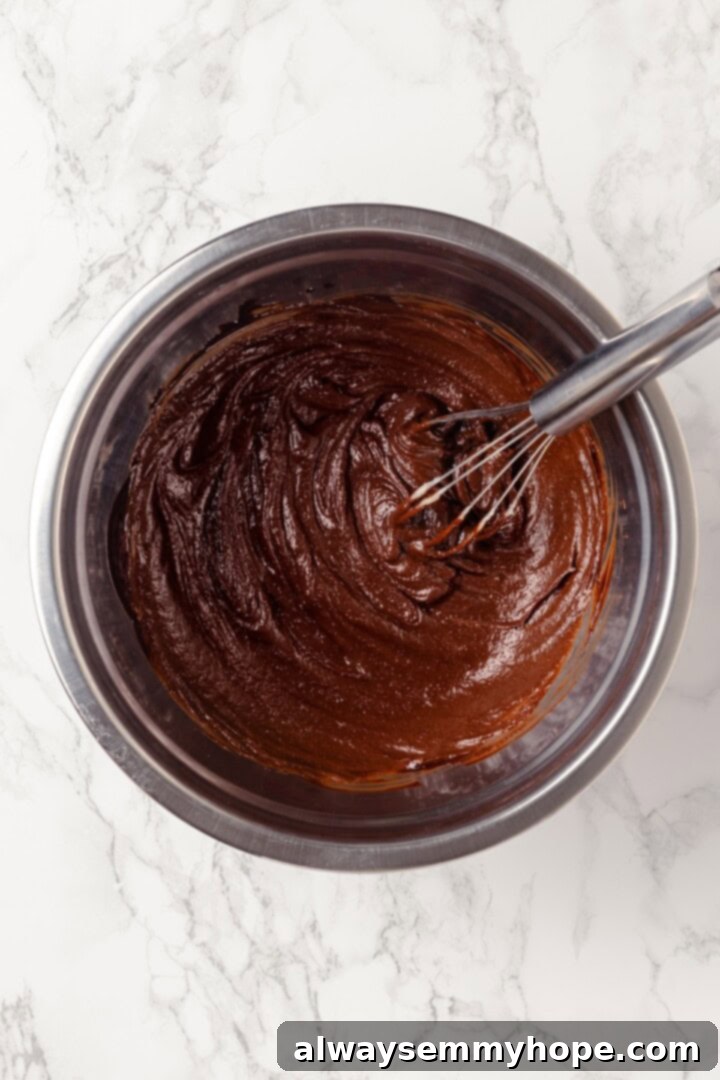 Overhead view of wet ingredients for cookie dough in bowl with whisk