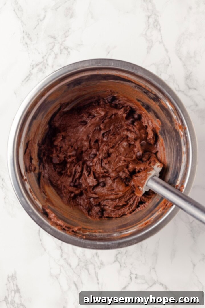 Overhead view of brownie cookie dough in bowl with rubber spatula