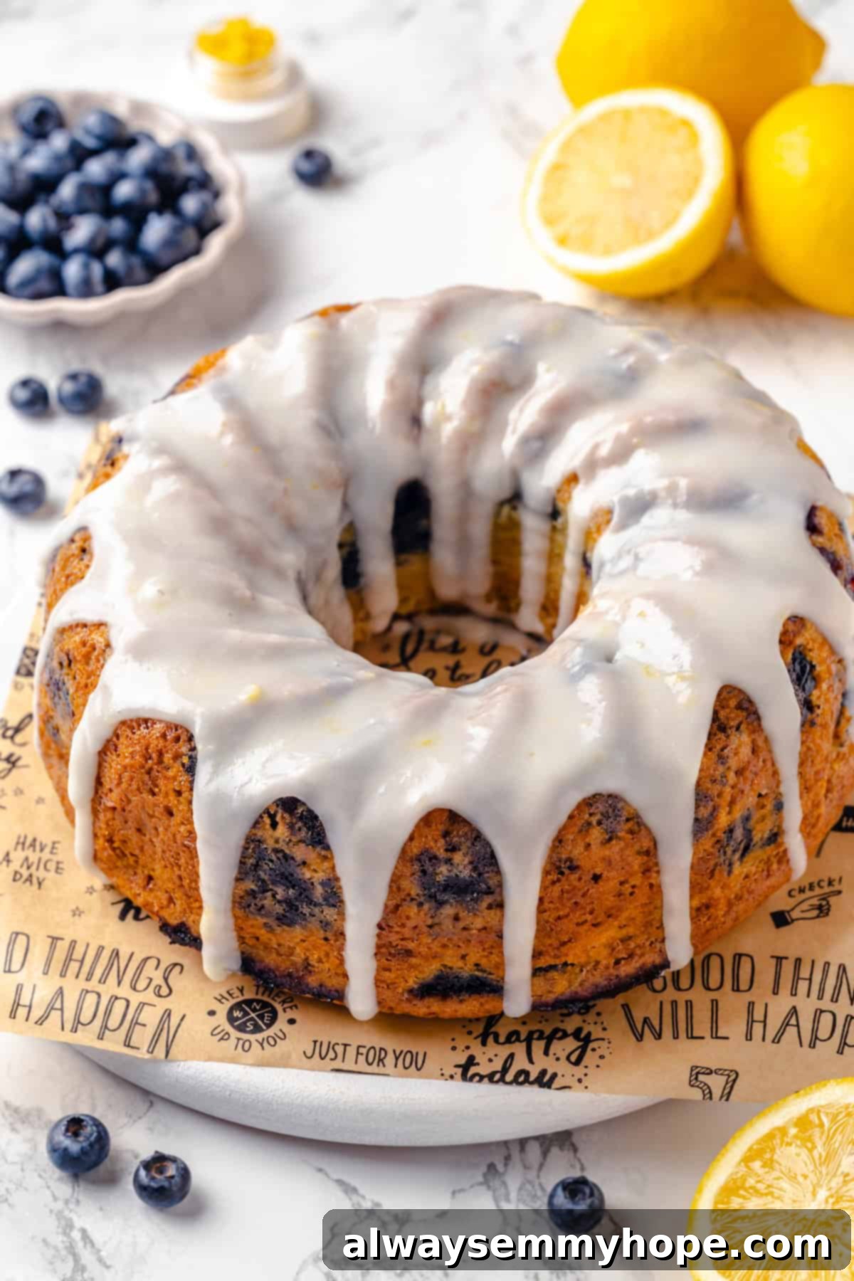 A whole lemon blueberry Bundt cake with glaze, ready to serve. A beautifully glazed whole lemon blueberry Bundt cake presented on a parchment-lined platter, ready to be served.