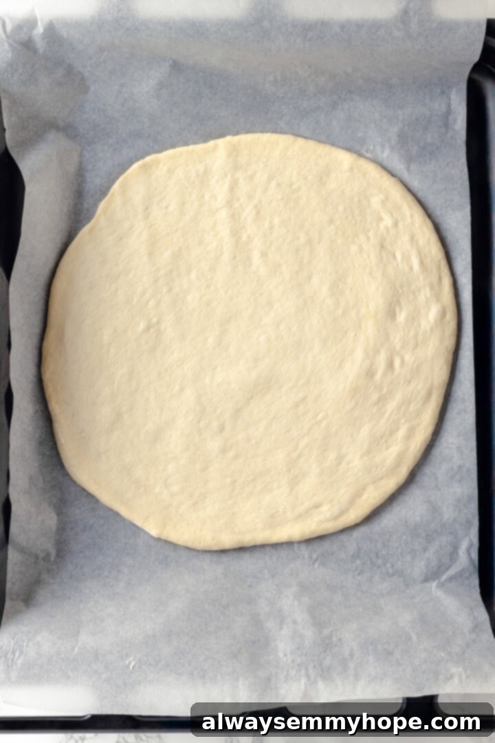 A creamy sauce makes this Alfredo sauce pizza taste indulgent, but it’s vegan! Plant-based chicken and bacon take this recipe over the top. Overhead view of a pizza crust perfectly transferred onto a baking pan before adding any toppings.