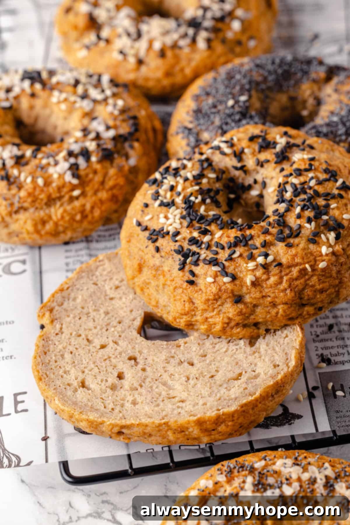 These homemade gluten-free bagels are chewy, delicious, and perfect for finishing with all your favourite toppings. So easy to make too! Sliced halves of a gluten-free bagel on wire rack