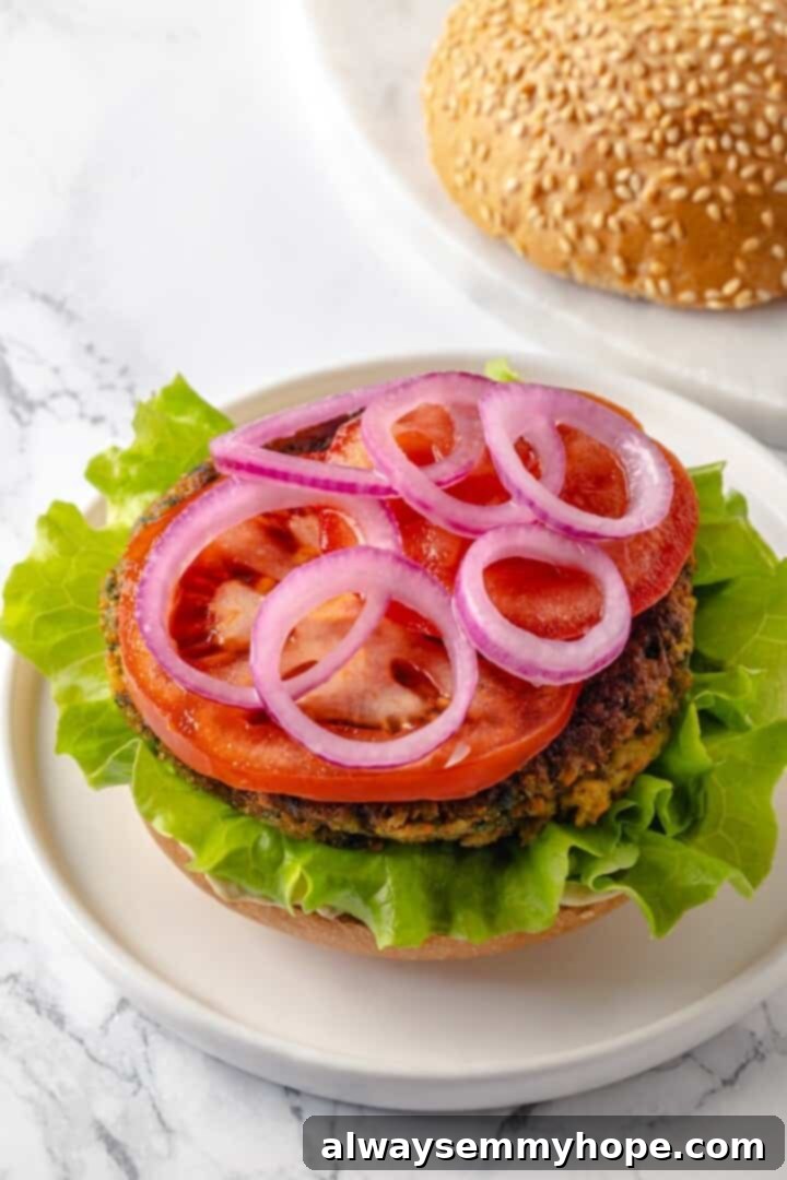 Falafel burger patty topped with vibrant pickled red onions, lettuce, and tomato slices.