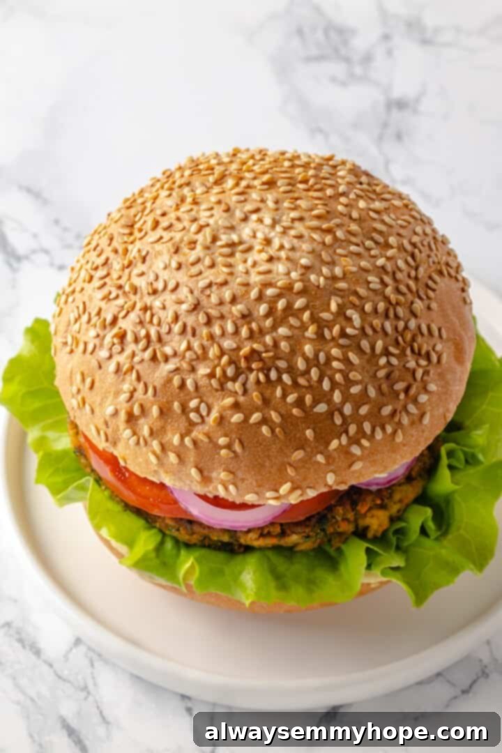 Top-down view of a perfectly assembled vegan falafel burger, complete with all its fresh toppings and a toasted bun.