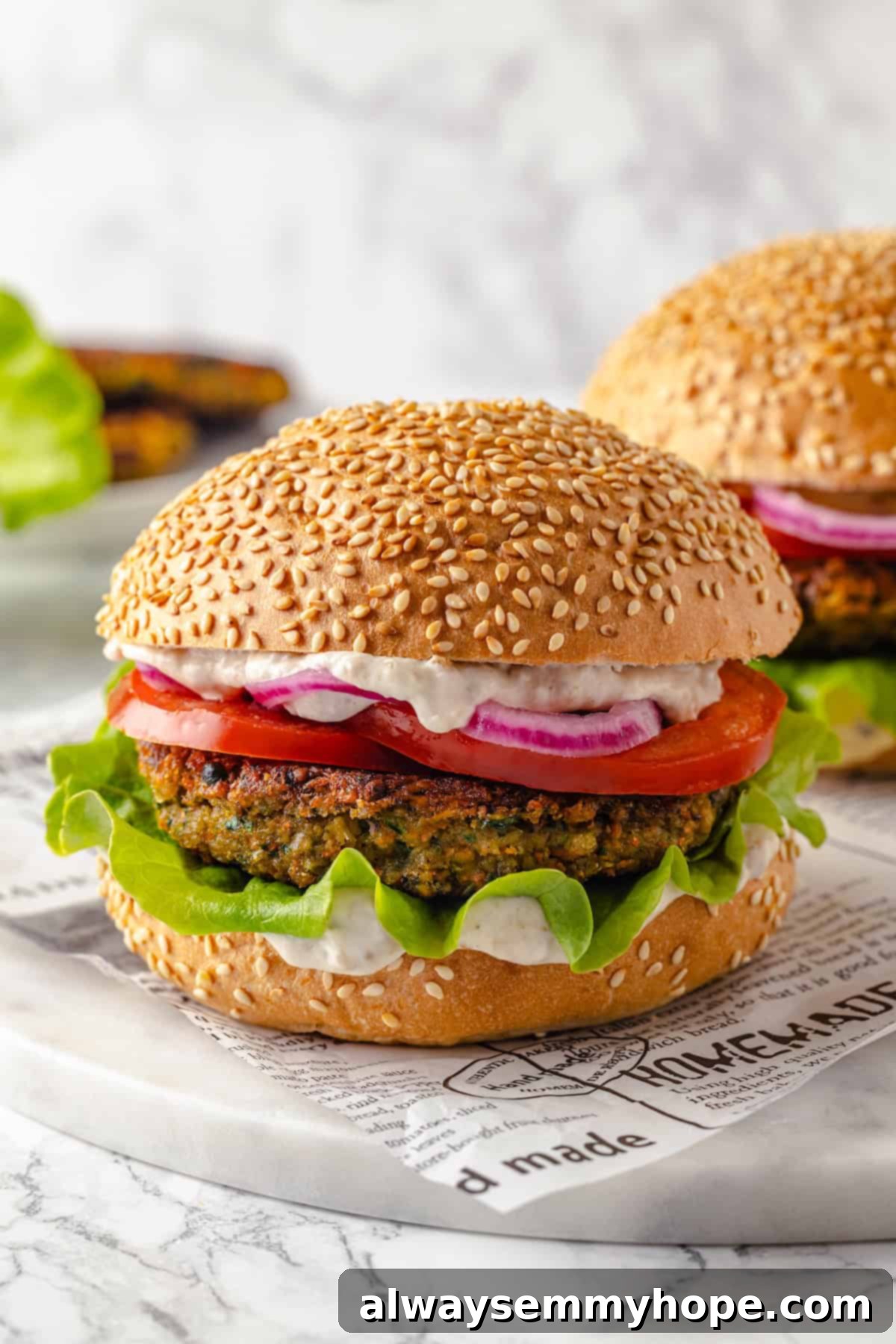 Two perfectly assembled vegan falafel burgers on sesame seed buns, garnished and ready to serve.