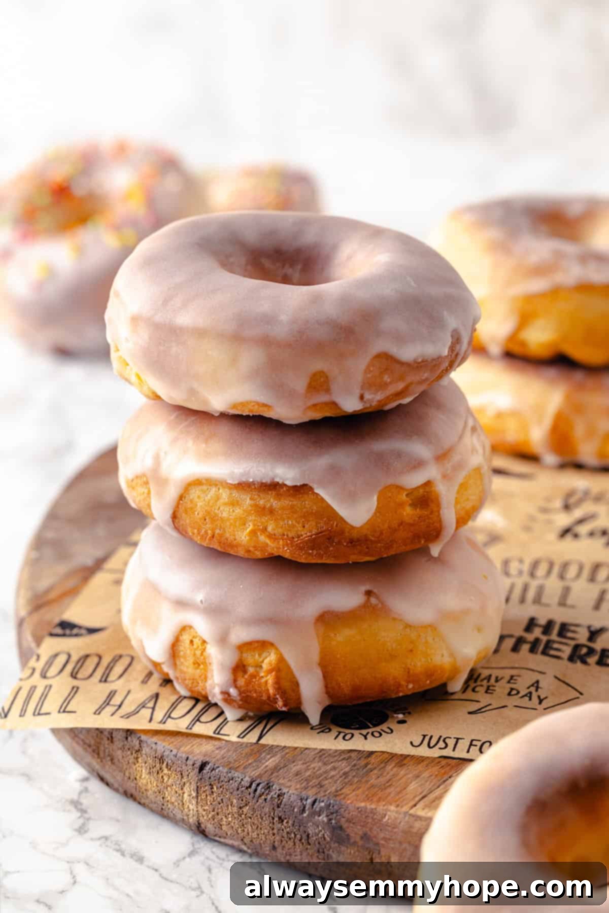 Stack of three perfectly golden and glazed air fryer donuts on a parchment-lined wooden board, ready to be enjoyed.