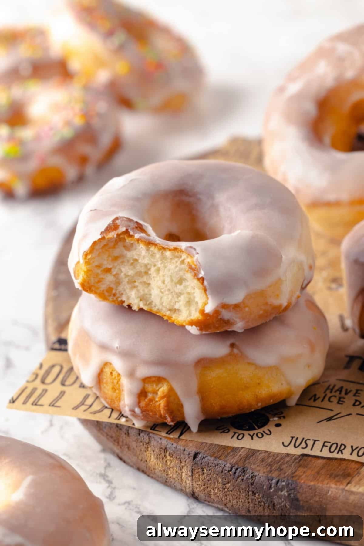 Two air fryer donuts stacked on top of each other, with the top donut bitten into to reveal its fluffy, airy interior and sweet glaze.
