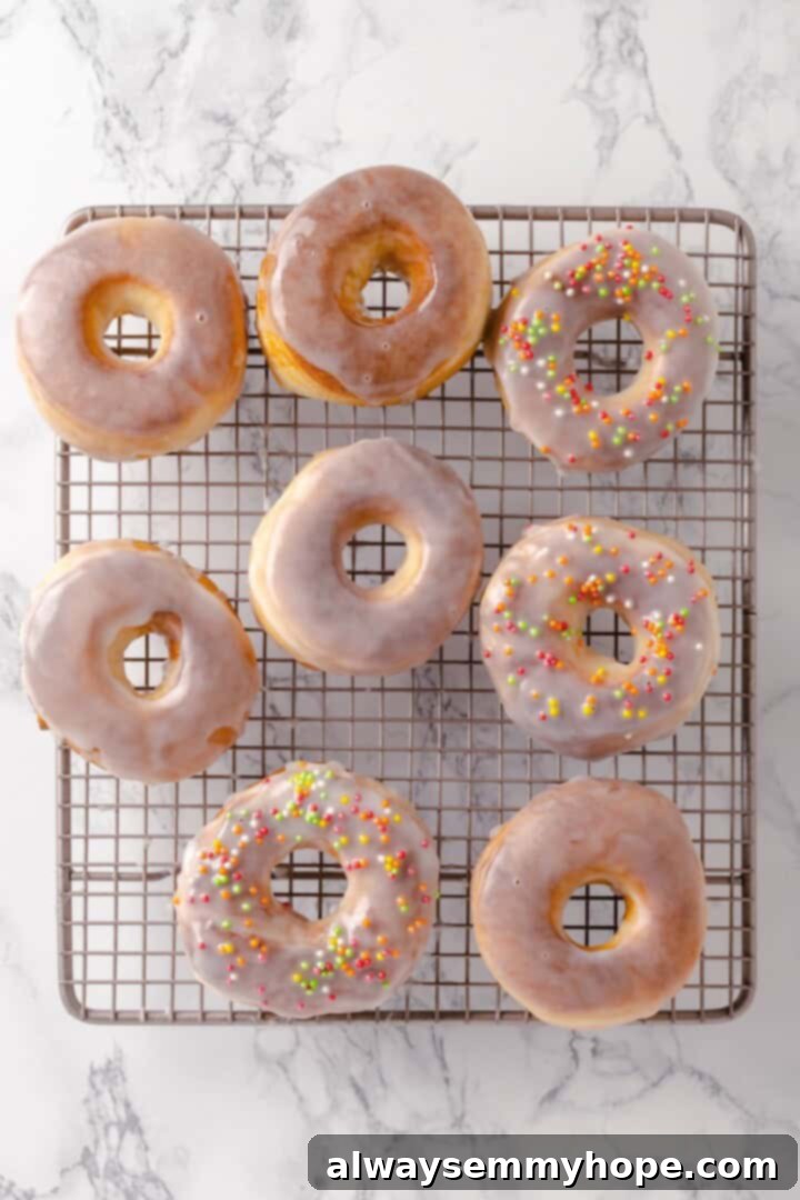 Overhead view of vegan air fryer donuts cooling on a wire rack, with some already glazed and others ready for dipping.