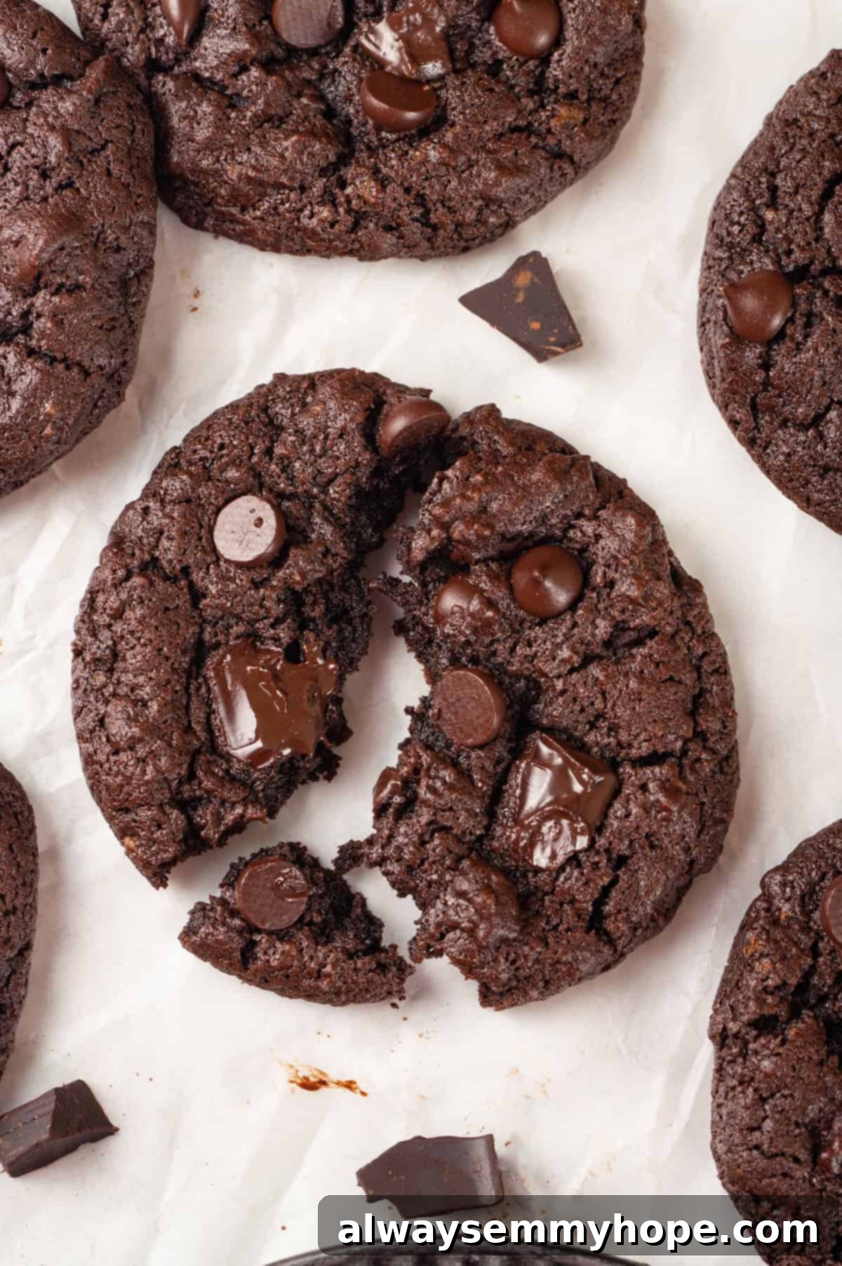 These double chocolate chunk cookies feature a rich, chewy chocolate cookie dough loaded with chocolate chips and dark chocolate chunks. Yum! Overhead view of double chocolate chunk cookie broken into 3 pieces