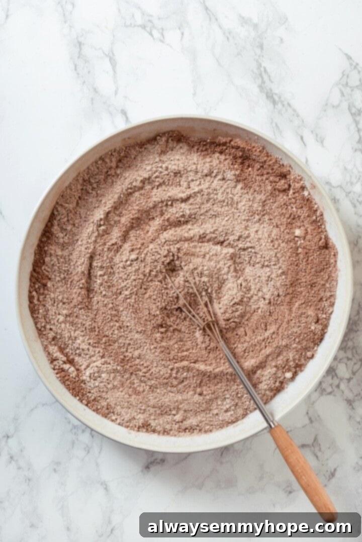 These double chocolate chunk cookies feature a rich, chewy chocolate cookie dough loaded with chocolate chips and dark chocolate chunks. Yum! Overhead view of dry ingredients in mixing bowl with whisk