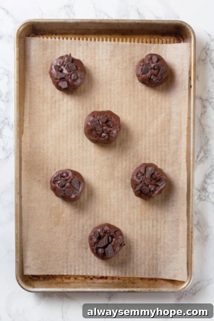 These double chocolate chunk cookies feature a rich, chewy chocolate cookie dough loaded with chocolate chips and dark chocolate chunks. Yum! Overhead view of double chocolate chunk cookie dough on parchment-lined baking sheet