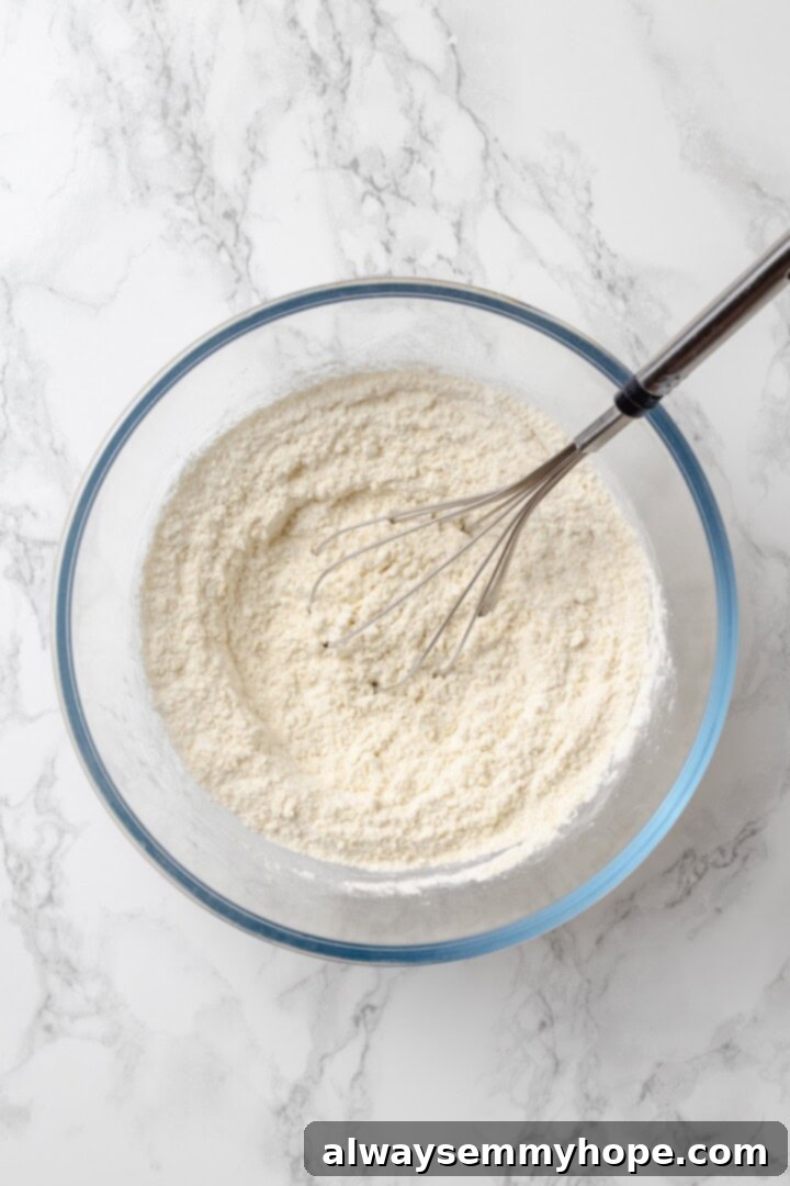 This homemade gluten-free English muffin recipe is tender, golden, and perfect for adding your favourite jam or spread. They're vegan too! Glass bowl containing potato starch, tapioca starch, millet flour, and salt being whisked together.