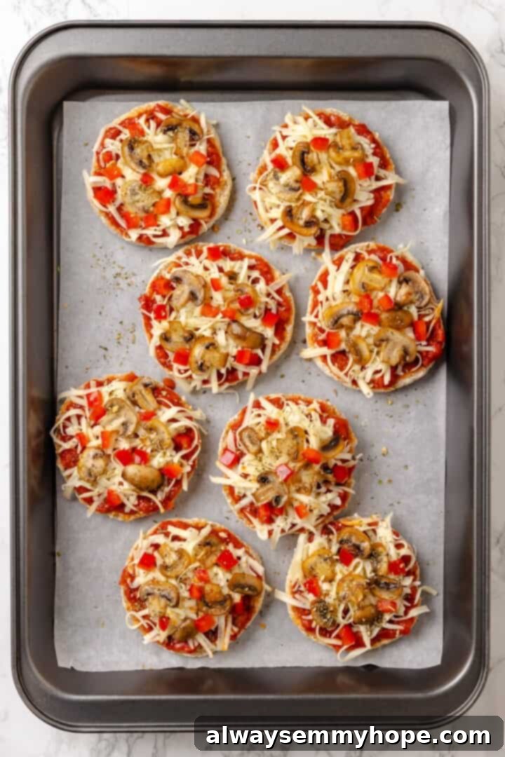 Overhead view of English muffin pizzas on baking sheet before baking